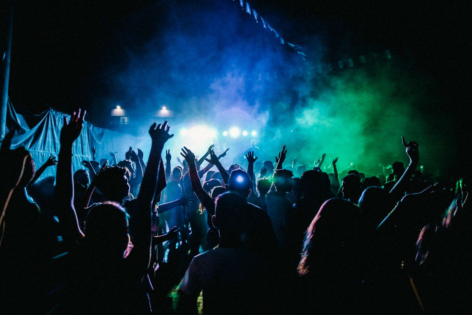 A crowd with raised hands in front of a lit stage