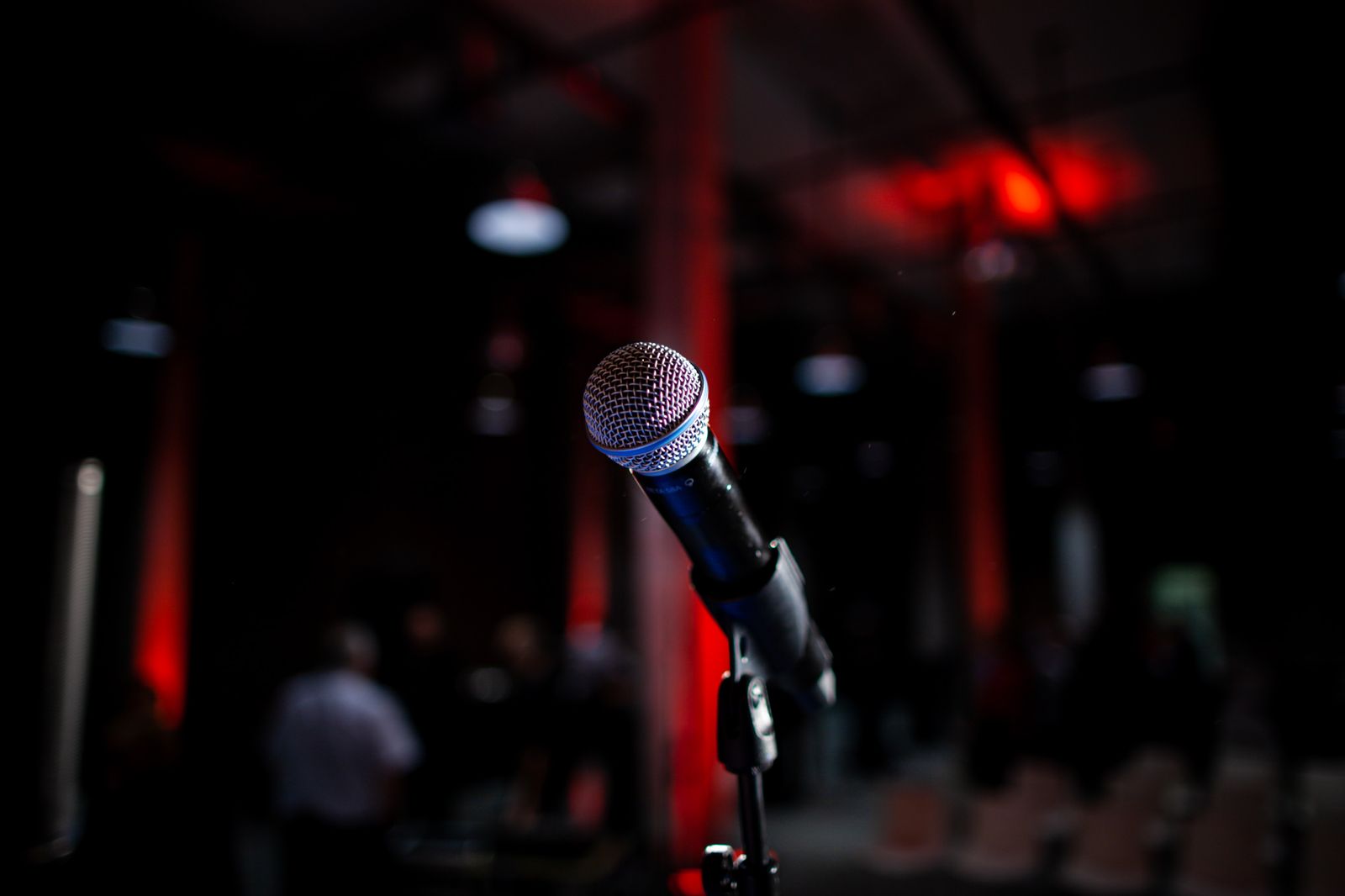 A microphone on a stand under red stage lights